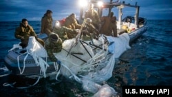 FILE - This image provided by the U.S. Navy shows sailors assigned to Explosive Ordnance Disposal Group 2 recovering a high-altitude surveillance balloon off the U.S. coast of Myrtle Beach, South Carolina, Feb. 5, 2023.