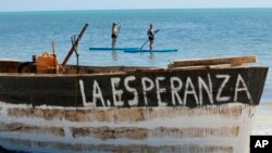 FILE - Paddleboarders draw close to get a better look at a beached migrant boat named La Esperanza, Spanish for 'hope, on Coco Plum Beach in Marathon, Fla., Jan. 19, 2023.
