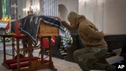 A soldier mourns at the coffin of Eduard Lobau, a Belarusian volunteer soldier who was killed defending Donetsk region, in Kyiv, Ukraine, Feb. 4, 2023. 