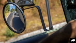 FILE - Trucks loaded with avocados are seen reflected on a rear view mirror as they are escorted by the police on their way to the city of Uruapan, in Santa Ana Zirosto, Michoacan state, Mexico, Jan. 26, 2023.