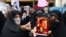 FILE - A protester shows a cartoon of French President Emmanuel Macron during a protest condemning the French magazine Charlie Hebdo for republishing cartoons insulting Iran's Supreme Leader Ayatollah Ali Khamenei, in Tehran, Iran, Jan. 11, 2023.