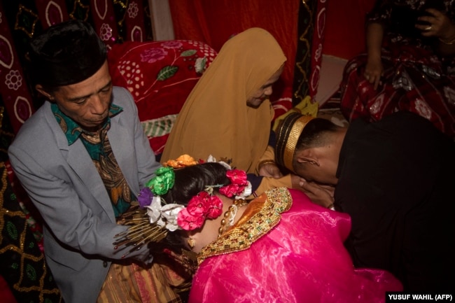 Dua remaja meminta restu orang tua setelah menikah di desa Tampapadang di Mamuju, Sulawesi Barat. (Foto: AFP)