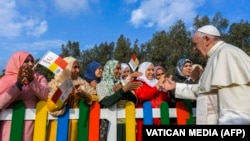 FILE - This photo was taken and handout by the Vatican press office, Vatican Media, on March 31, 2019 shows Pope Francis blessing Moroccan women upon his arrival for a visit to the Rural Center for Social Services at Temara, south of Rabat, during the pontiff's two-day visit to Morocco.