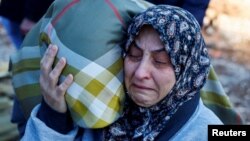 A woman reacts as people bury victims of the deadly earthquake, in a cemetery in Kahramanmaras, Turkey, Feb. 9, 2023.