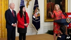 First lady Jill Biden speaks as President Joe Biden and Elaine Tso, CEO of Asian Services in Action, listen during a reception to celebrate the Lunar New Year in the East Room of the White House in Washington, Jan. 26, 2023.