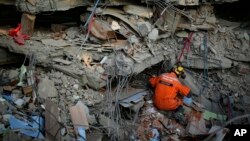 দক্ষিণ তুরস্কের আদিয়ামানের একটি ধসে পড়া ভবন পরীক্ষা করছেন একজন তুর্কী উদ্ধারকর্মী। ১১ ফেব্রুয়ারি, ২০২৩। 