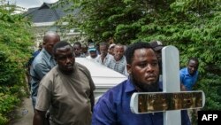 Mourners proceed bearing a cross and a coffin with the body of Tanzanian student, Nemes Tarimo, whose body arrived at his homeplace in Dar es Salaam, Tanzania, after he was killed fighting for Russia in Ukraine after being recruited in jail.