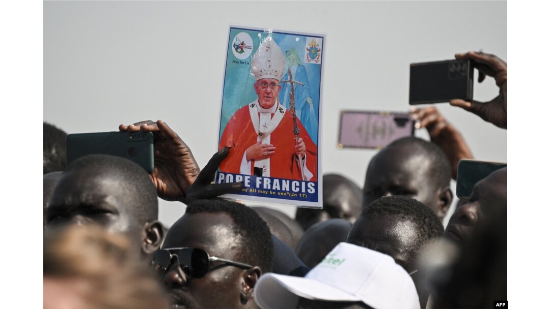 Seorang pria memegang foto Paus Fransiskus saat kerumunan orang berkumpul untuk menyambutnya setibanya di Bandara Internasional Juba di Juba, Sudan Selatan. (Foto: AFP)