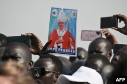Seorang pria memegang foto Paus Fransiskus saat kerumunan orang berkumpul untuk menyambutnya setibanya di Bandara Internasional Juba di Juba, Sudan Selatan. (Foto: AFP)