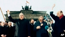FILE - West German Chancellor Helmut Kohl, left, waves as he stands with then East German Prime Minister Hans Modrow, second right, in front of the Brandenburg Gate, Dec. 22. 1989.