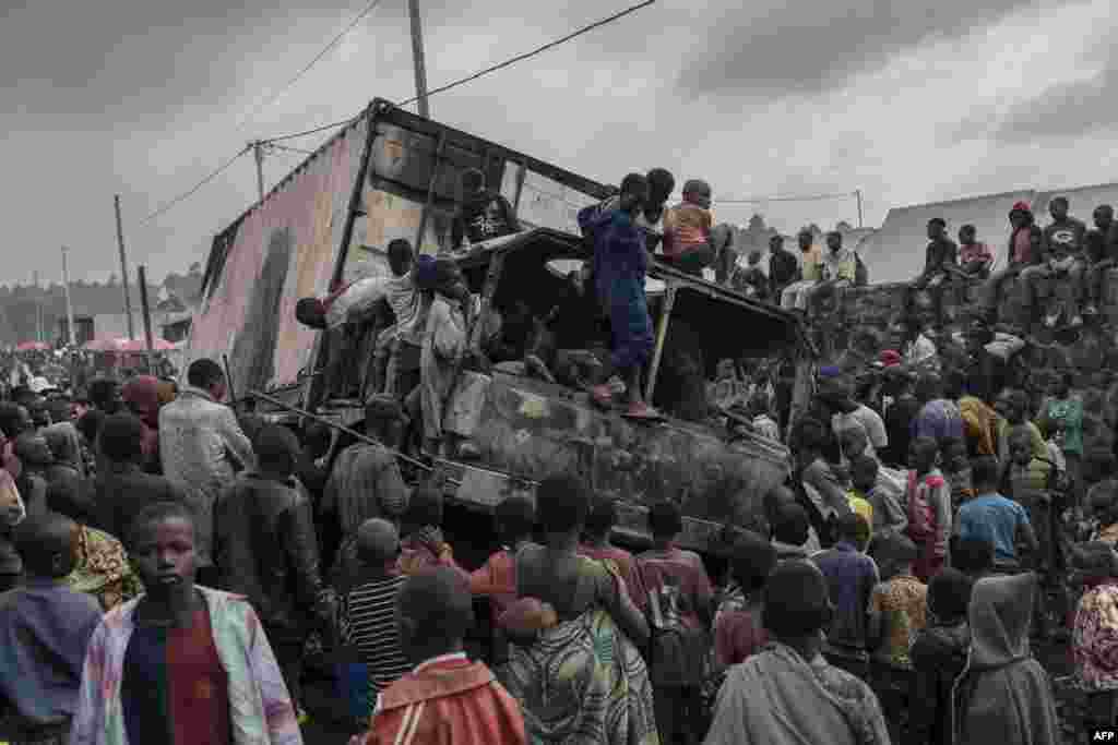 People dismantle a vehicle belonging to the United Nations Stabilization Mission in the Democratic Republic of Congo in Kanyaruchinya, Nyiragongo territory, after it was set on fire overnight by angry residents.