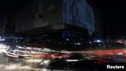 Vehicle lights create light streaks on a road along a market, during a country-wide power outage, in Karachi, Pakistan, Jan. 23, 2023.