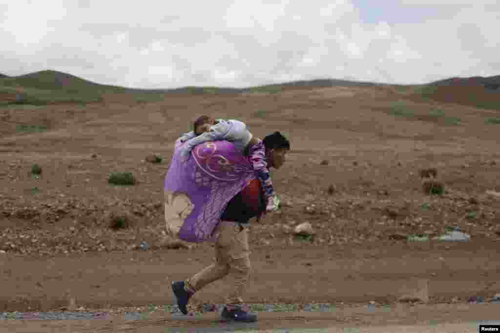 A man carries his daughter as he walks near a road block made by anti-government protesters to demand Peru&#39;s President Dina Boluarte to step down, in Condoroma in Cusco region, Feb. 4, 2023.