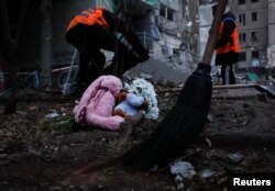 Tributes lie on the ground as emergency personnel work at the site where an apartment block was heavily damaged by a Russian missile strike in Dnipro, Ukraine, Jan. 16, 2023.