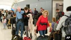 FILE - Travelers wade through the line to drop off bags at the Southwest Airlines check-in counter at Denver International Airport, Dec. 27, 2022, in Denver.
