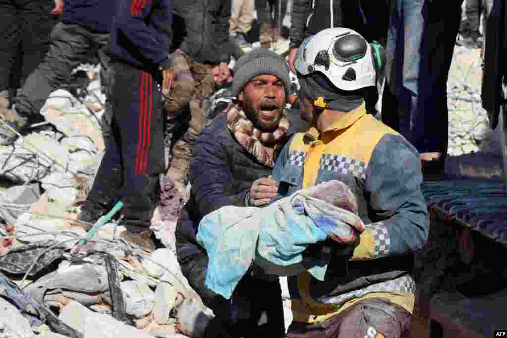 A man reacts as the body of his baby pulled out from the rubble, is taken away by a Syrian White Helmet rescue worker, in the town of Harim in Syria&#39;s rebel-held northwestern Idlib province, Feb. 8, 2023.