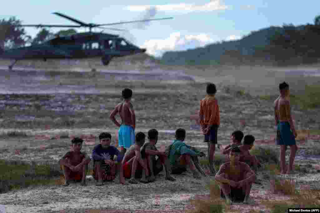 Desde la proclamación del estado de emergencia sanitaria en la comunidad Yanomami, que ocupa la mayor reserva indígena de Brasil, la ayuda ha sido transportada por la Fuerza Aérea hasta los asentamientos nativos, donde niños observan la llegada de un helicóptero militar al aeropuerto de Surucucu en territorio Yanomami, el 28 e enero de 2023.&nbsp;