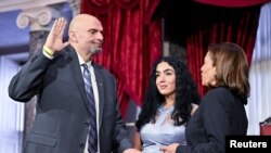 FILE - Senator John Fetterman is ceremonially sworn into office by Vice President Kamala Harris as Fetterman's wife Gisele holds the Bible during a reenactment in the Old Senate Chamber, at the US Capitol in Washington, Jan. 3, 2023. 