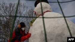 北京降雪后一名男子搭起一个雪人。(2023年1月23日)
