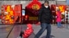 A man pulls a child past a Lunar New Year decoration on display at the Qianmen pedestrian shopping street, a popular tourist spot in Beijing, Jan. 17, 2023. 