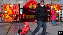 A man pulls a child past a Lunar New Year decoration on display at the Qianmen pedestrian shopping street, a popular tourist spot in Beijing, Jan. 17, 2023. 