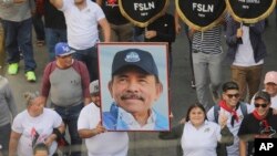 FILE - A man marches holding a portrait of President Daniel Ortega during a pro-government march in Managua, Nicaragua, Feb. 11, 2023.