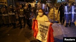 Seorang pengunjuk rasa memegang bendera di depan polisi anti huru hara yang berjaga saat berlangsungnya aksi protes menuntut Presiden Peru Dina Boluarte mundur, di Lima, Peru, 31 Januari 2023. (REUTERS/Sebastian Castaneda)