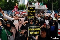 Umat Muslim Indonesia membawa plakat dalam aksi protes atas pembakaran Al-Qur'an di Swedia, di luar Kedutaan Besar Swedia di Jakarta, 30 Januari 2023. (REUTERS/Willy Kurniawan)