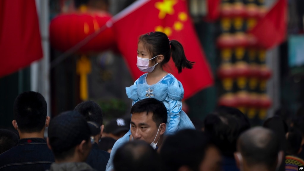 资料照:在北京一个购物区一名小女孩骑在一个男子的肩头上逛街。(2022年10月7日)