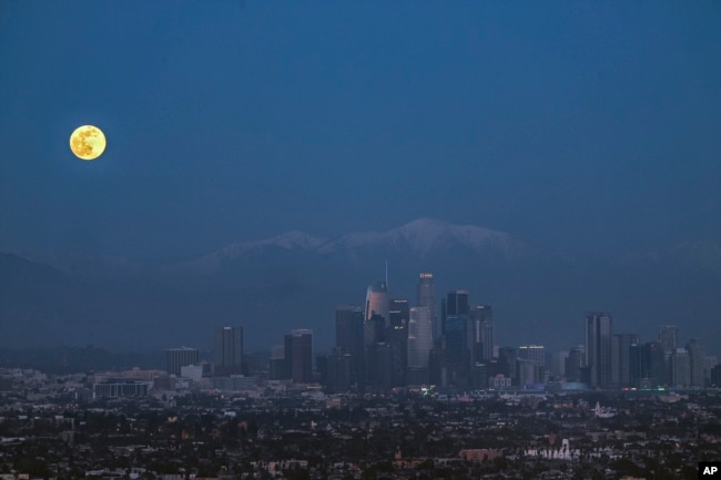 The new year's first moon rises over the Los Angeles skyline on Friday, Jan. 6, 2023. (AP Photo/Damian Dovarganes)