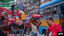 Laborers unload sealed sacks of spices at a wholesale market in Kolkata on Feb. 1, 2023.