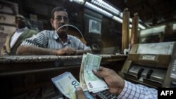FILE: An employee counts banknotes at a currency exchange shop in the Egyptian capital Cairo on November 3, 2016. - With Egypt's economy in crisis, the currency in freefall and inflation skyrocketing, the poor have been hit hard but the middle class is also strongly affected.