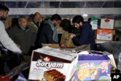 Volunteers carry food boxes to distribute to displaced people following a devastating earthquake, in Latakia, Syria, Feb. 10, 2023.