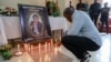 A mourner places a candle in a room of Radio Amplitude FM where a portrait of journalist Martinez Zogo has been placed to pay tribute to him, in Yaounde, Cameroon, on Jan. 23, 2023.