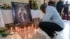 A mourner places a candle in a room of Radio Amplitude FM where a portrait of journalist Martinez Zogo has been placed to pay tribute to him, in Yaoundé, Cameroon, on Jan. 23, 2023.