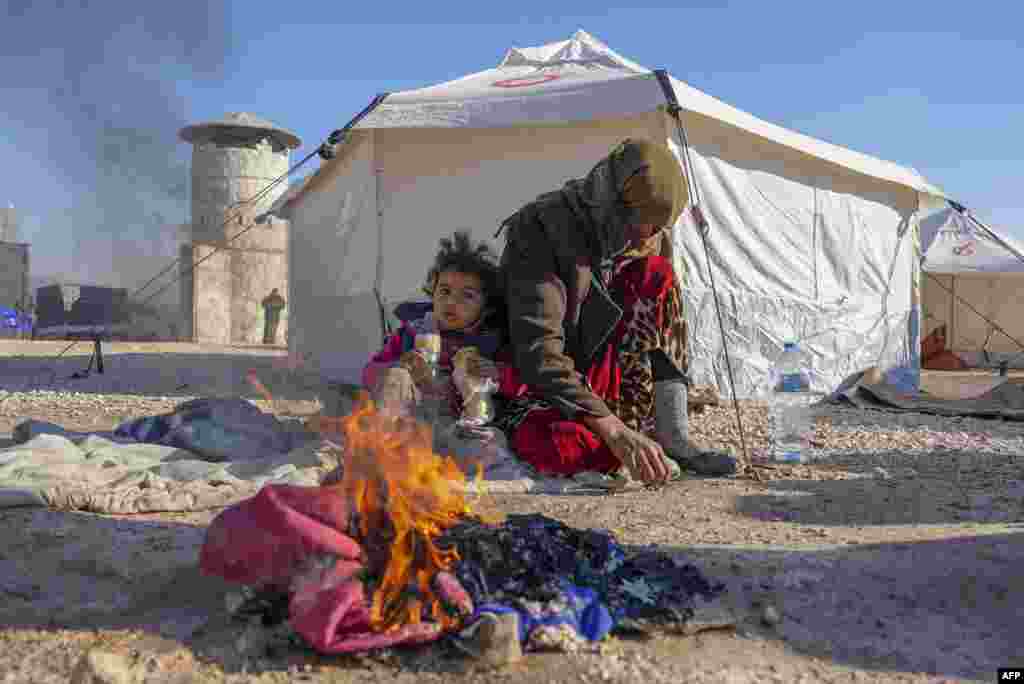 Сиријците се топлат на оган во импровизираното засолниште за луѓето кои останаа без покрив над главата по смртоносниот земјотрес што ги погоди Турција и Сирија.