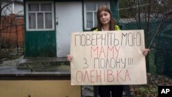 Alina Kapatsyna holds a poster that reads: "Bring back my mom from captivity," written in Ukrainian, in Dnipro, Ukraine, Jan. 6, 2023. Men in military uniforms took 45-year-old Vita Hannych away from her house in eastern Ukraine in April. 