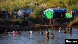 FILE - Refugees, who have fled fighting in Myanmar, bathe in the river on the Thai-Myanmar border, in Mae Sot, Thailand, Jan. 7, 2022. 