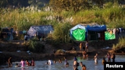 FILE - Refugees, who have fled fighting in Myanmar, bathe in the river on the Thai-Myanmar border, in Mae Sot, Thailand, Jan. 7, 2022. 