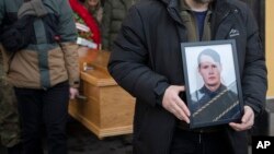 Soldiers and friends carry the coffin and photo of Eduard Lobau, a Belarusian volunteer soldier who was killed defending Donetsk region, in Kyiv, Ukraine, Feb. 4, 2023