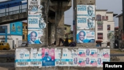A man sleeps under a bridge decorated with electoral campaign posters, ahead of Nigeria's presidential elections, in Lagos, Nigeria, Jan. 31, 2023.