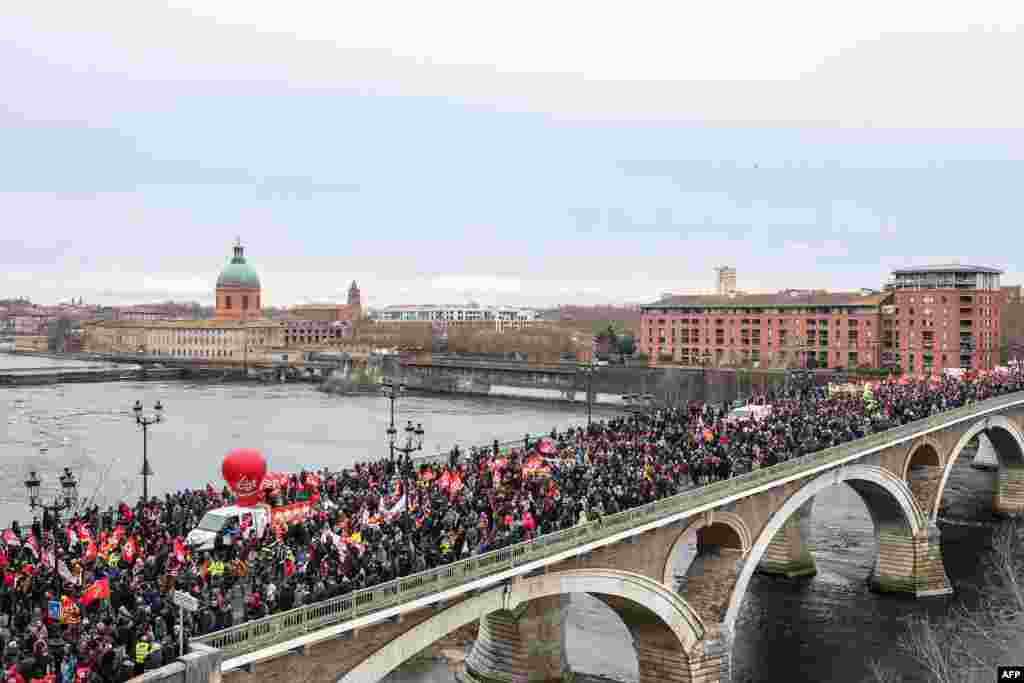 Demonstrators walk on the Catalans bridge during a protest on the third day of nationwide rallies against a deeply unpopular pensions overhaul in Toulouse, France.