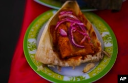 A Cochinita Pibil style tamal is displayed during theTamales fair at the Ixtapalapa neighborhood of Mexico City, Friday, Jan. 27, 2023. Cochinita pibil is a traditional Yucatec Mayan slow-roasted pork dish from the Yucatán Peninsula. (AP Photo/Fernando Llano)