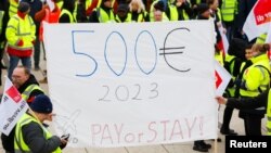 Demonstran memegang spanduk selama pemogokan umum oleh karyawan atas tuntutan gaji, di Bandara Berlin Brandenburg (BER), di Schoenefeld dekat Berlin, Jerman 25 Januari 2023. (REUTERS/Michele Tantussi)