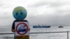 A member of Extinction Rebellion holds up a placard as the 'Akademik Alexander Karpinsky', a Russian polar explorer ship, arrives in Cape Town harbor, South Africa, Jan. 28, 2023. 