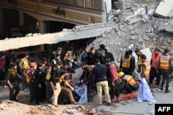 Petugas penyelamat membawa sisa-sisa korban ledakan dari puing-puing masjid yang rusak setelah ledakan di dalam markas polisi di Peshawar pada 30 Januari 2023. (Foto: AFP)