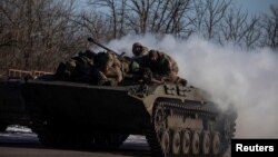 Ukrainian service members ride atop of a BMP-2 infantry fighting vehicle near a frontline in Donetsk region, Ukraine, Feb. 8, 2023.