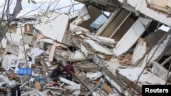 Warga berdiri di atas puing-puing saat pencarian korban usai gempa bumi mengguncang Turki di Provinsi Hatay, Turki, 7 Februari 2023. (Foto: Reuters)