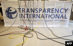 FILE - Microphone cables dangle over a logo of Transparency International during a press conference in Berlin, Sept. 23, 2008.