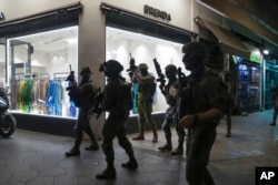 Israeli security forces search for assailants near the scene of a shooting attack in Tel Aviv, Israel, April 7, 2022.